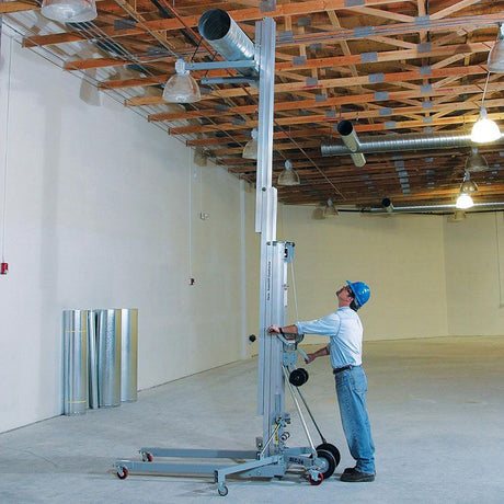 Genie material lift on a job site raising heavy equipment
