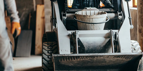 A skid steer concrete mixer attachment for pouring concrete on a job site.
